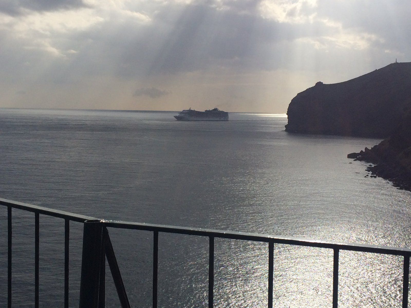A cruise ship passes the sea cliffs of Reis Magos seen from the terrace of Inn & Art restaurant, Canico de Baixo, Madeira