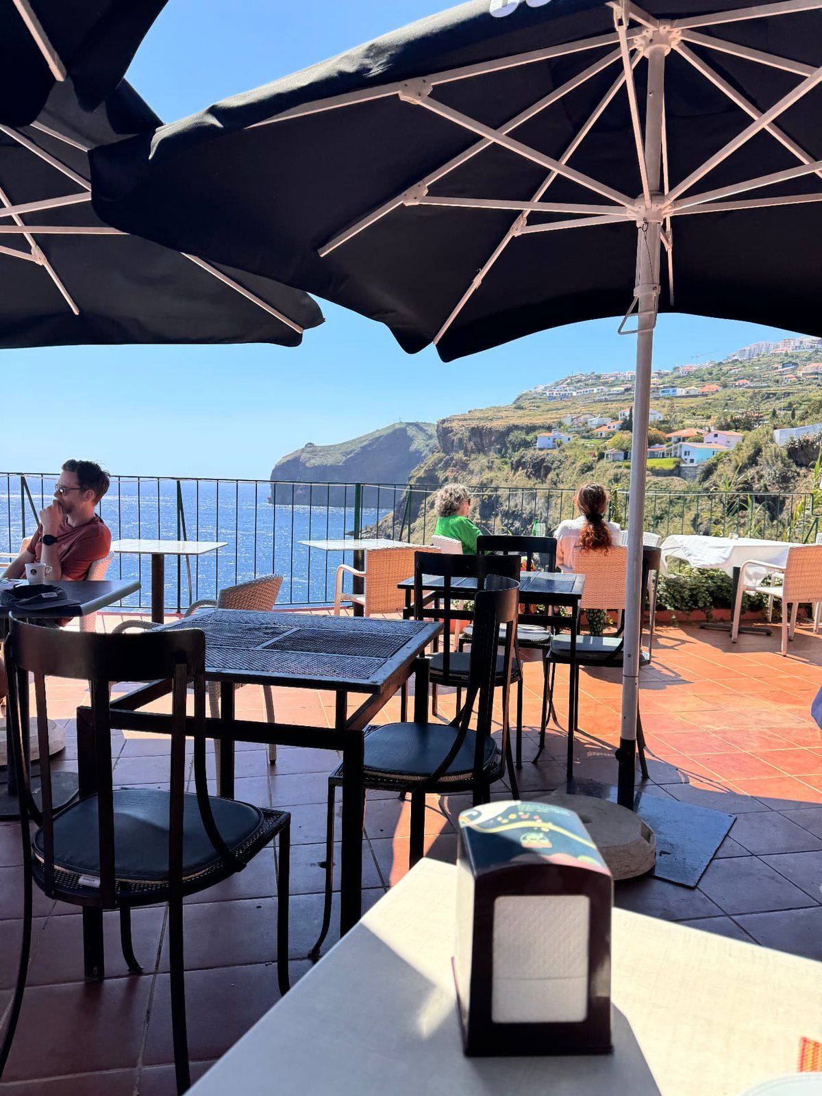 Shaded terrace tables at Inn & Art restaurant in Reis Magos, Canico de Baixo, overlooking the Atlantic and the Madeira coastline