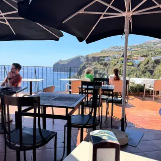Shaded terrace tables at Inn & Art restaurant in Reis Magos, Canico de Baixo, overlooking the Atlantic and the Madeira coastline