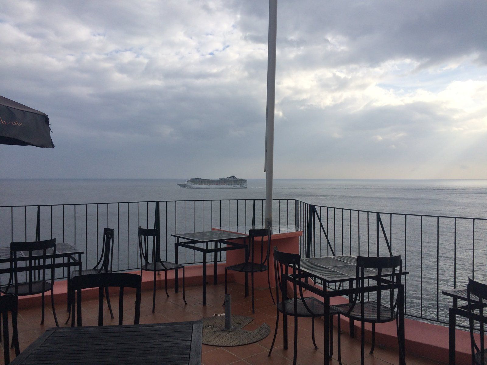 Mesas na esplanada do restaurante Inn & Art, em Reis Magos, com um navio de cruzeiro da MSC no horizonte, Caniço de Baixo, Madeira
