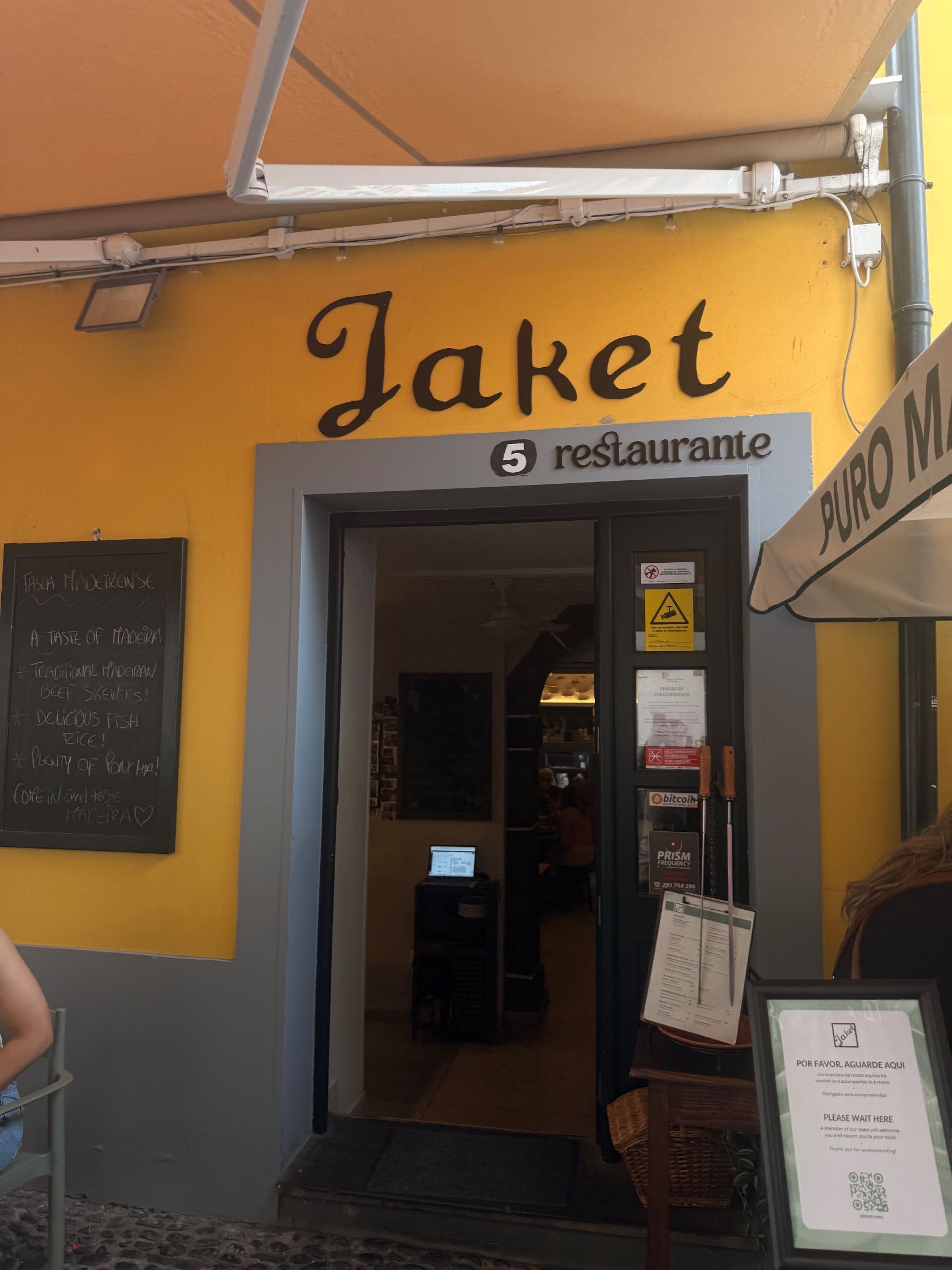 Jaket restaurant entrance with yellow walls, grey trim and a chalkboard beside the doorway