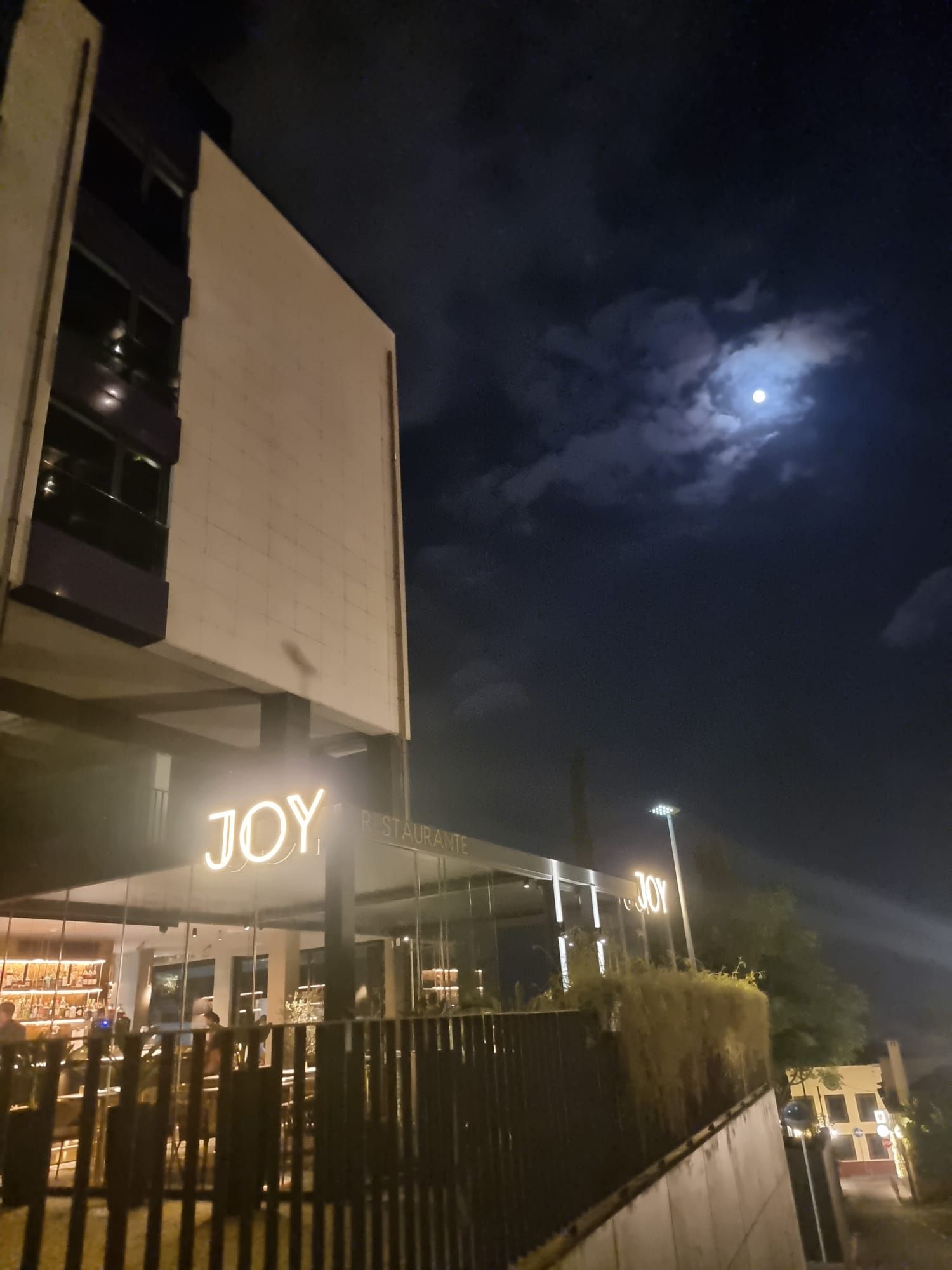 Exterior do restaurante Joy, no Funchal, à noite, com o letreiro iluminado