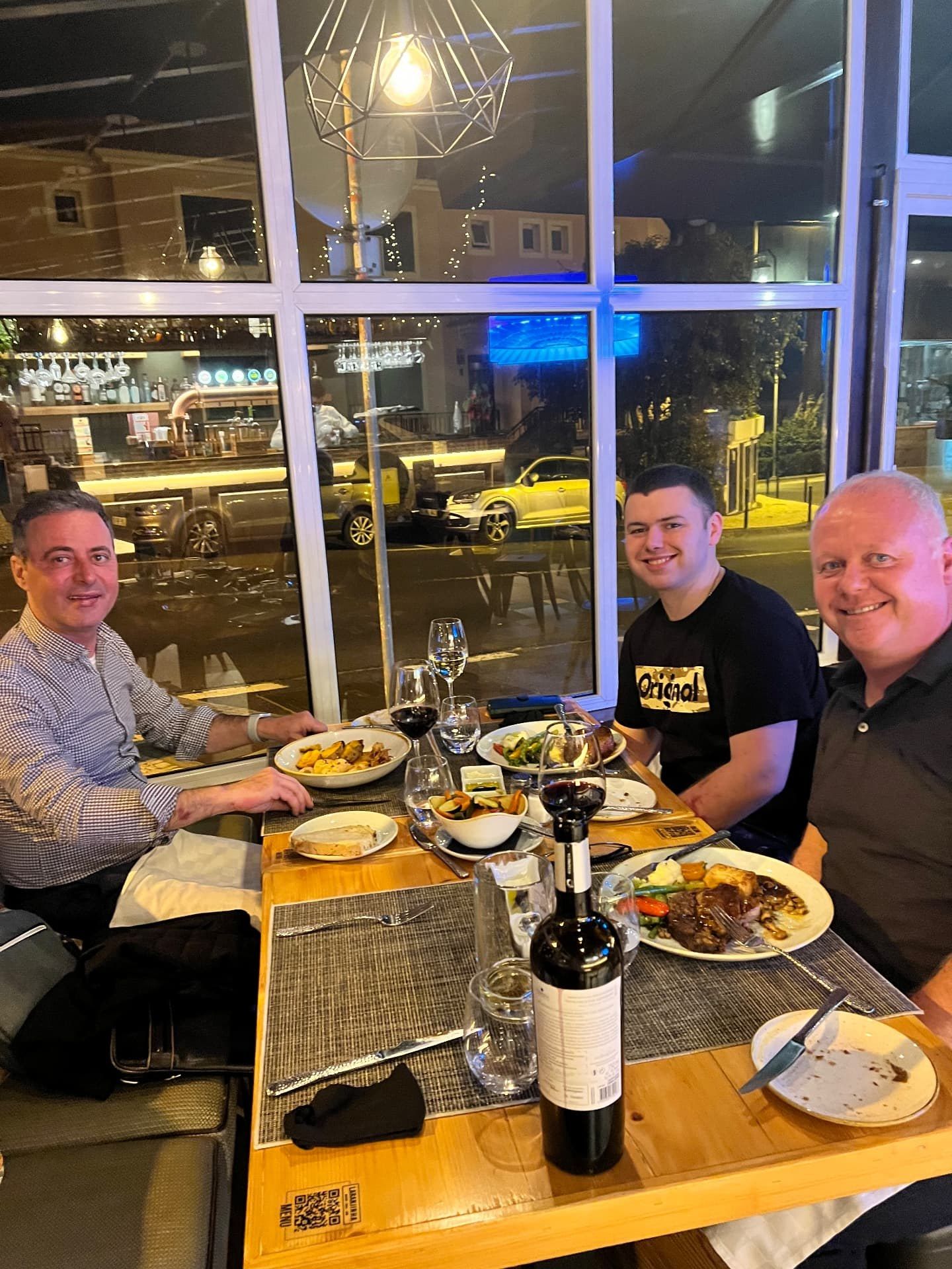 Amigos a desfrutar de um jantar acompanhado de vinho tinto ao fim da tarde no Laranjinha Bistro Grill, em Caniço de Baixo, na Madeira