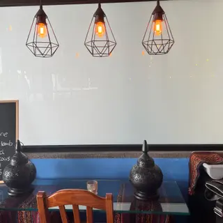 Restaurant table with pierced metal lanterns, wooden chairs and three geometric pendant lights