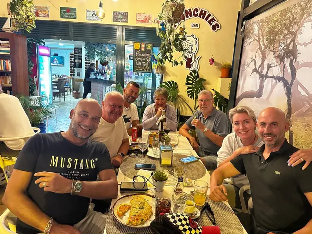 Friends enjoying dinner and drinks at Munchies Restaurante & Bar in Caniço, Madeira, with the bar's quirky decor and omelette dish on the table