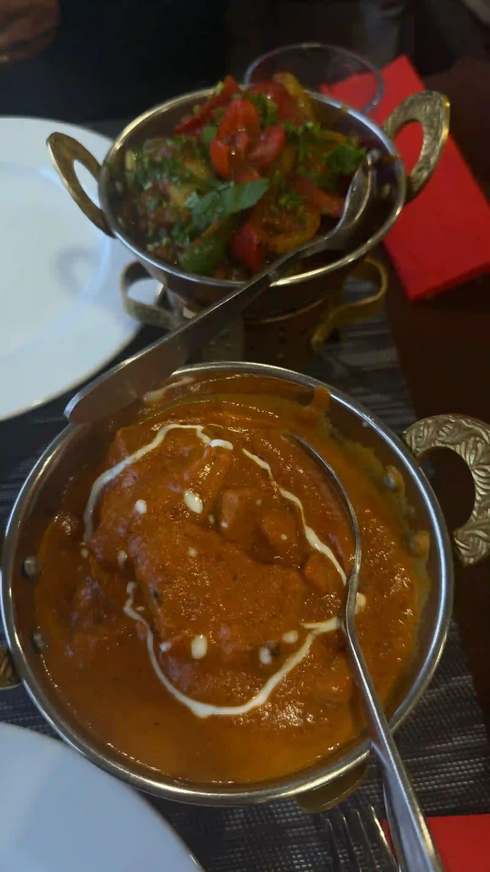Creamy chicken curry and a mixed vegetable curry served in brass-handled karahi bowls at Namaste India, Caniço