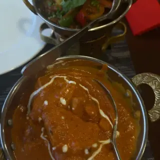 Creamy chicken curry and a mixed vegetable curry served in brass-handled karahi bowls at Namaste India, Caniço