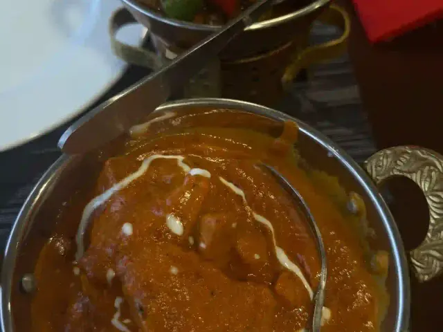 Creamy chicken curry and a mixed vegetable curry served in brass-handled karahi bowls at Namaste India, Caniço