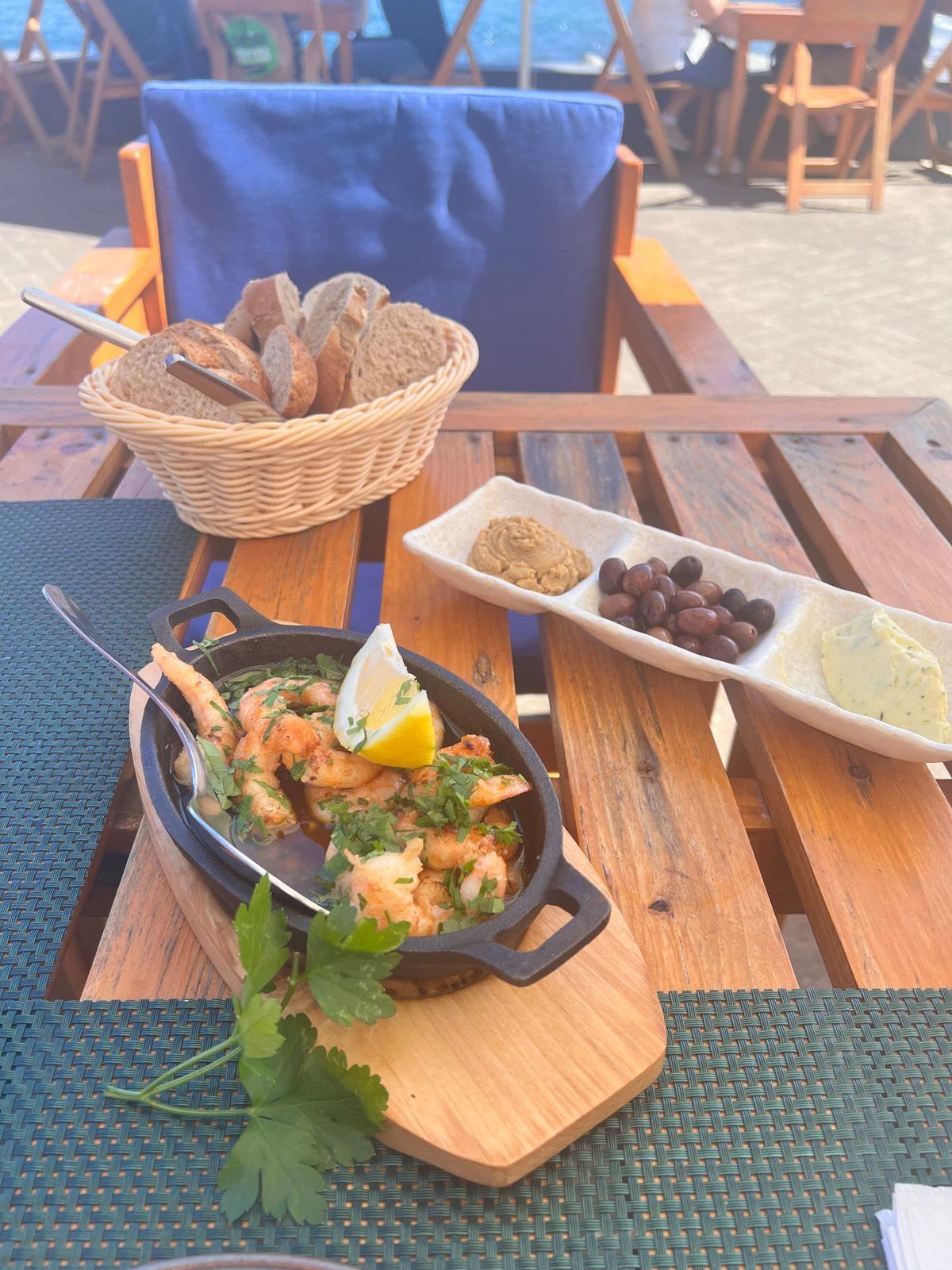 Sizzling garlic prawns with lemon and parsley, fresh bread, olives and herb butter on the seaside terrace of Praca do Engenho restaurant, Porto da Cruz, Madeira