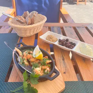 Sizzling garlic prawns with lemon and parsley, fresh bread, olives and herb butter on the seaside terrace of Praca do Engenho restaurant, Porto da Cruz, Madeira