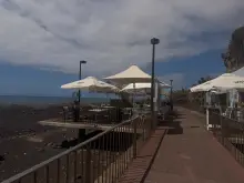 Seafront esplanade of Restaurante Praia Formosa with parasols right on the black pebble beach, Funchal