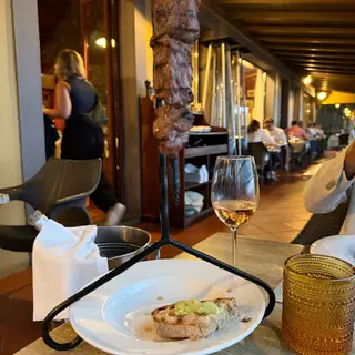 Traditional espetada beef skewer hanging over the table at Quinta do Furão restaurant, Santana, Madeira, with bolo do caco and Madeira wine