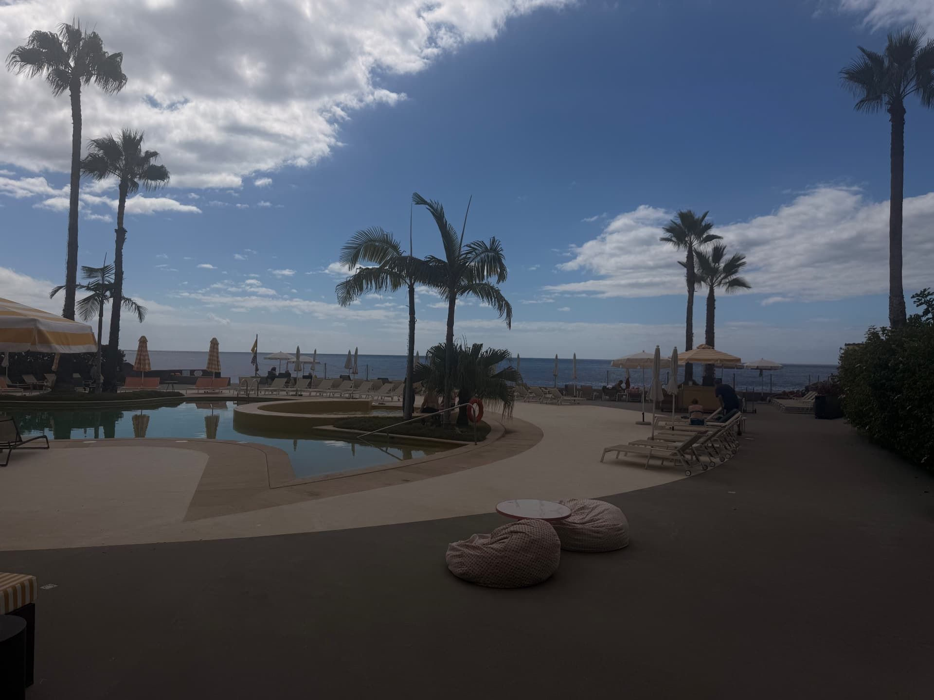 Pool deck at the NEXT Hotel by Recharge restaurant, with palm trees and the Atlantic beyond