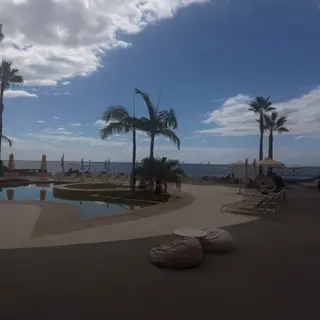 Pool deck at the NEXT Hotel by Recharge restaurant, with palm trees and the Atlantic beyond