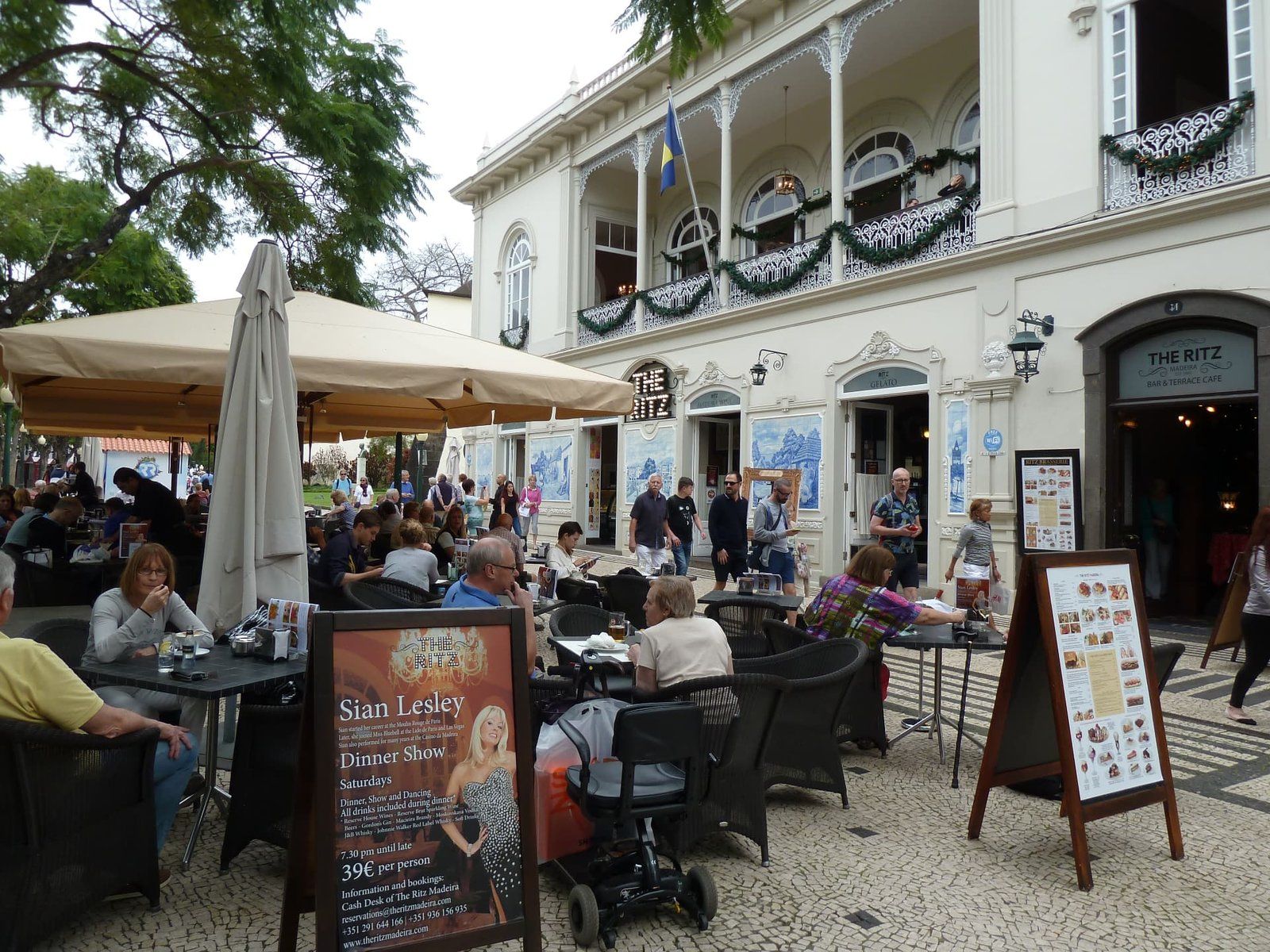 The busy esplanade of The Ritz Cafe on Avenida Arriaga in Funchal, Madeira, with its Belle Epoque facade and azulejo tile panels