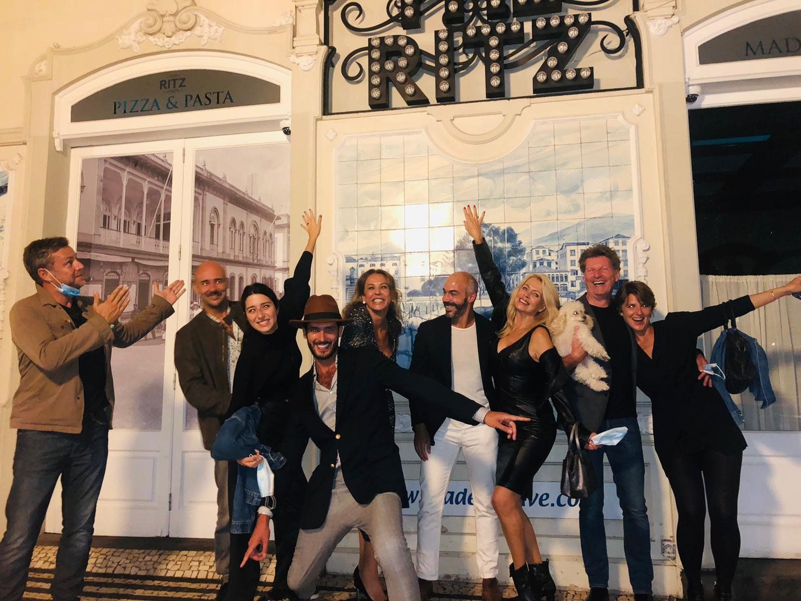 Um grupo celebra à noite à porta do The Ritz Madeira, sob o letreiro iluminado, após o jantar-espetáculo de sábado
