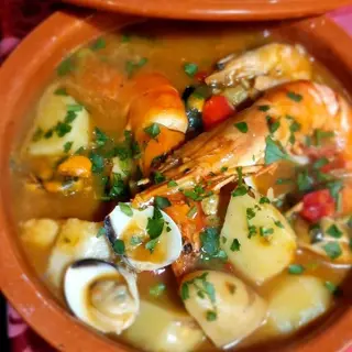 Caldeirada de marisco seafood stew with prawns, clams and potatoes served in a clay pot at Sabor a Fado restaurant, Funchal Old Town, Madeira