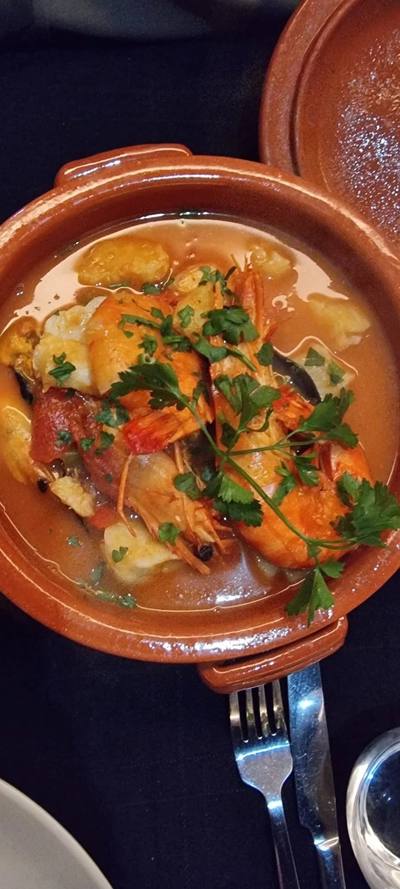 Close-up of seafood caldeirada with large prawns and clams in rich broth at Sabor a Fado, Funchal, Madeira
