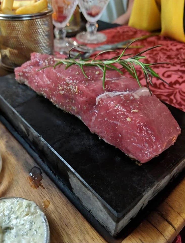 Raw steak served on a sizzling hot volcanic stone with rosemary and fries at Sabor a Fado restaurant, Funchal, Madeira
