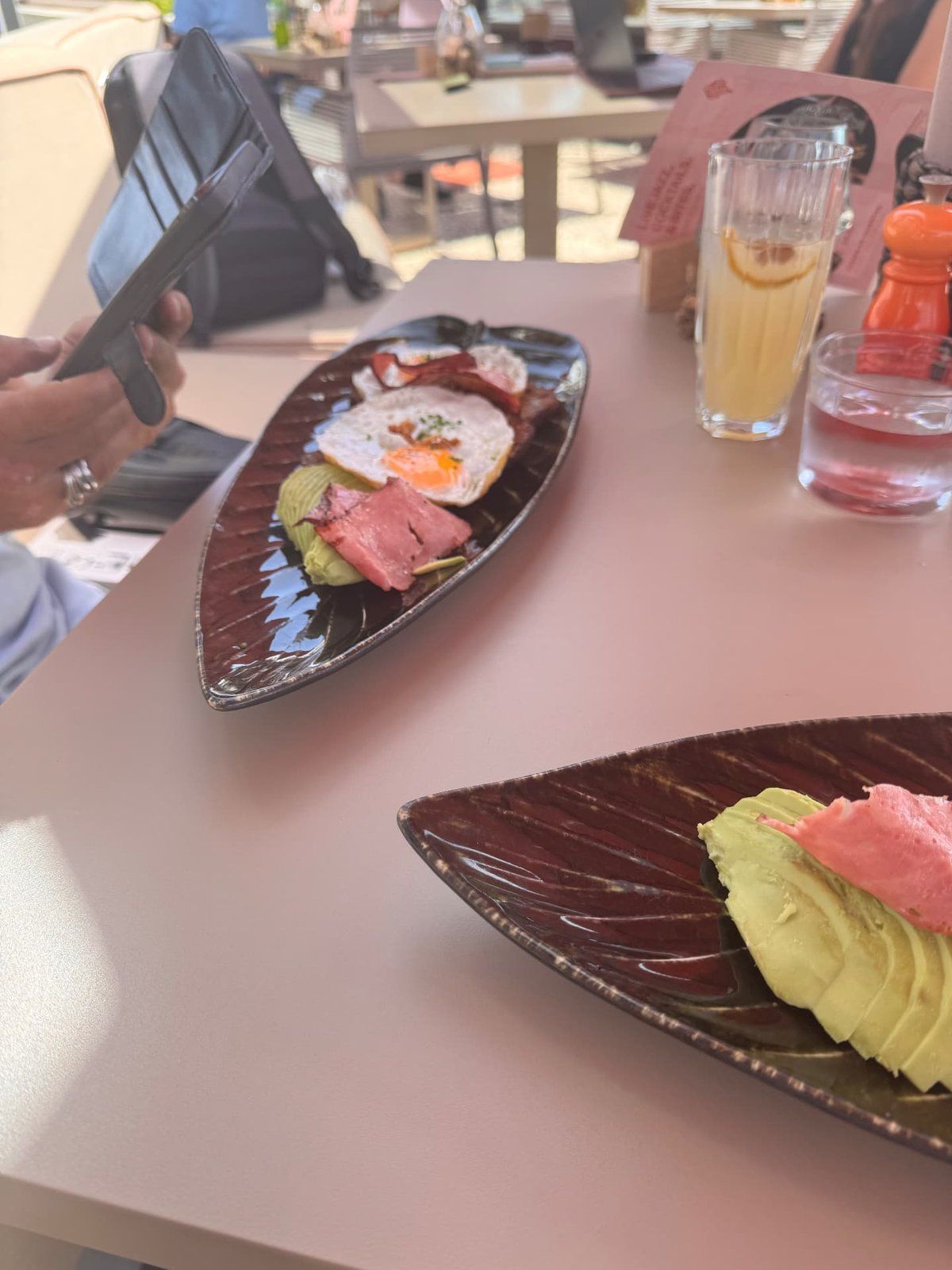 Weekend brunch plates at Three House restaurant in Funchal, Madeira, with fried egg, bacon and avocado, and fresh juice on the table