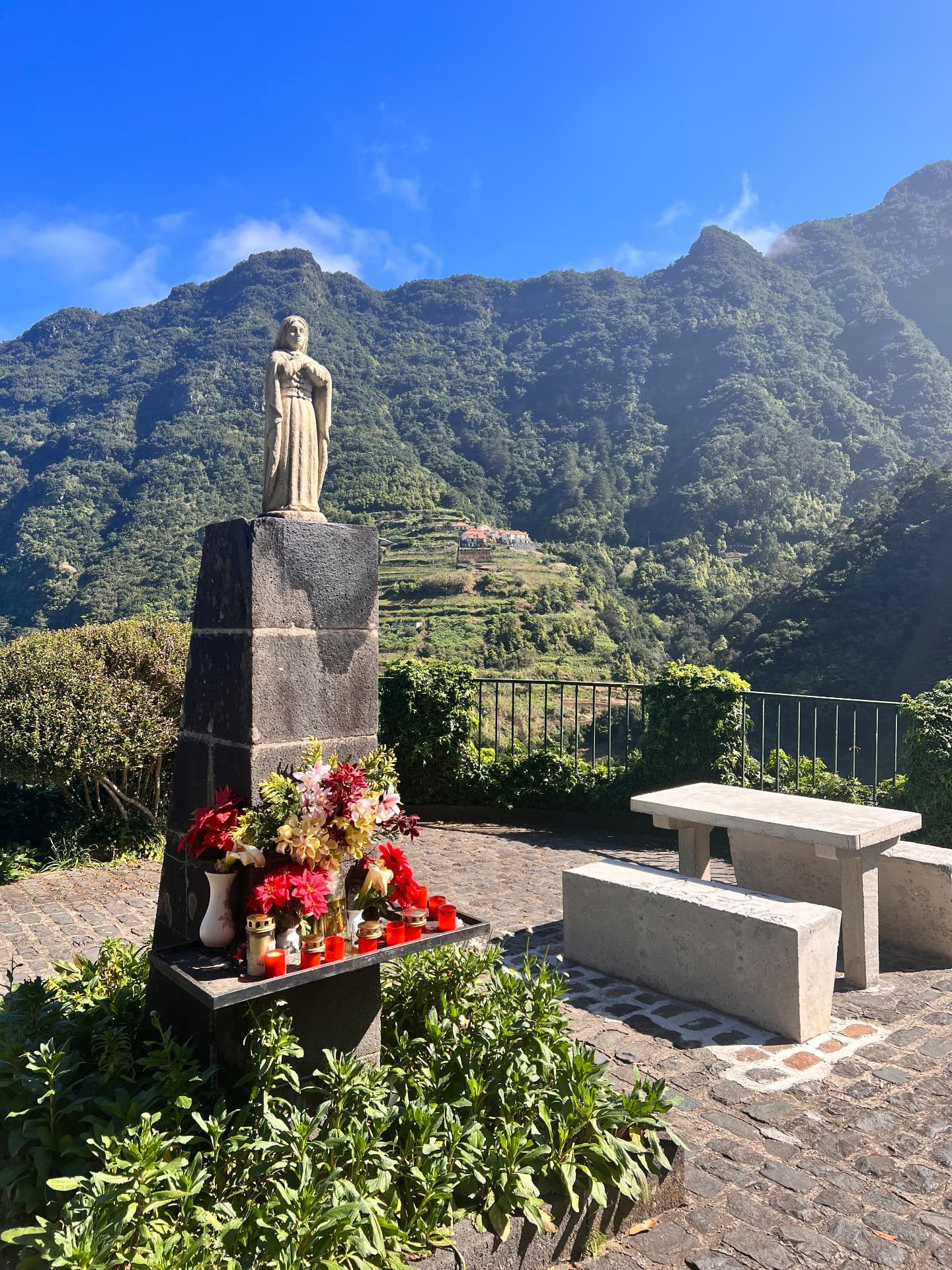 Statue and flower-decked shrine at the Boaventura viewpoint with terraced mountains behind