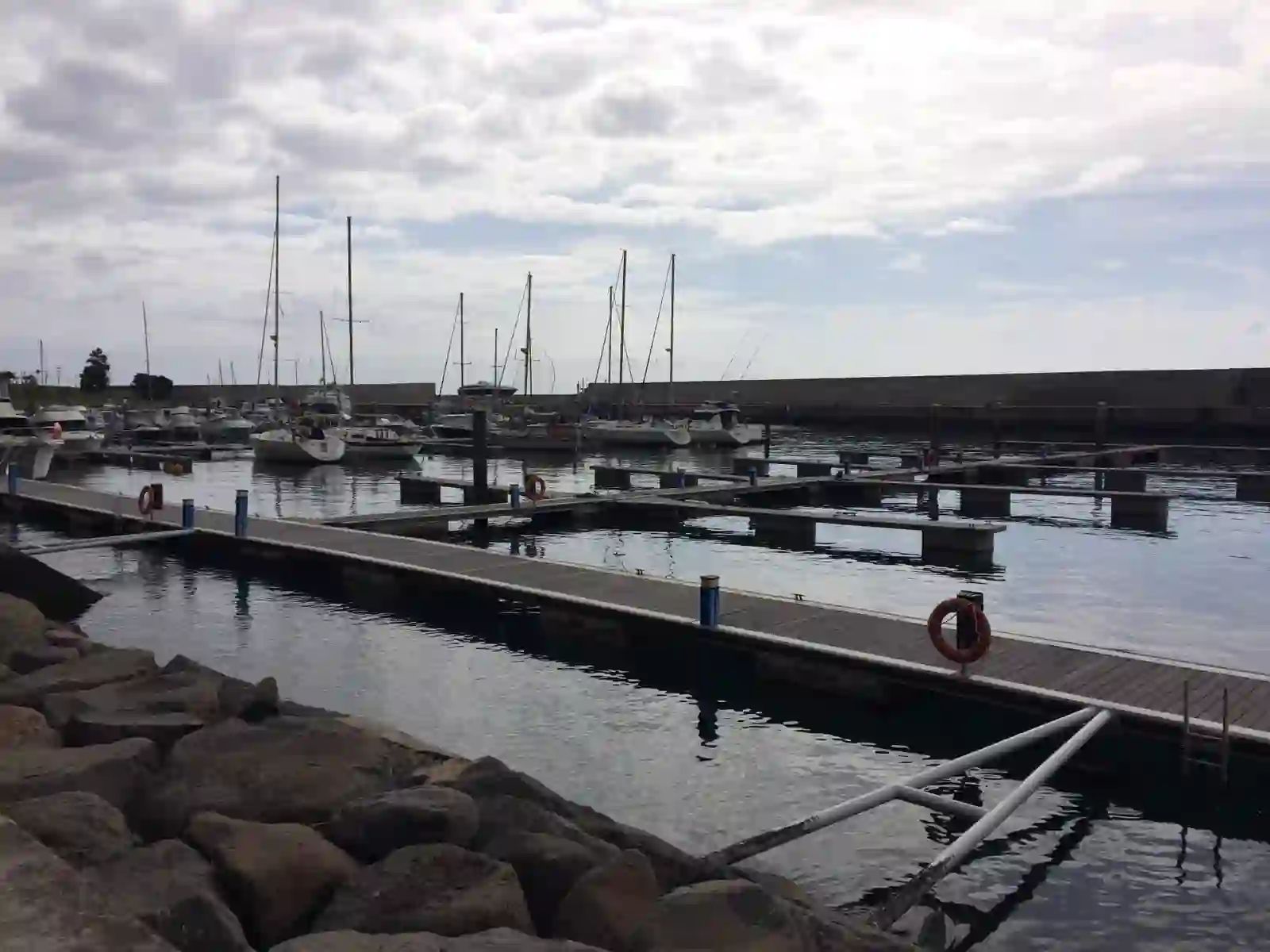 Iates e barcos a motor atracados em pontões na marina da Calheta