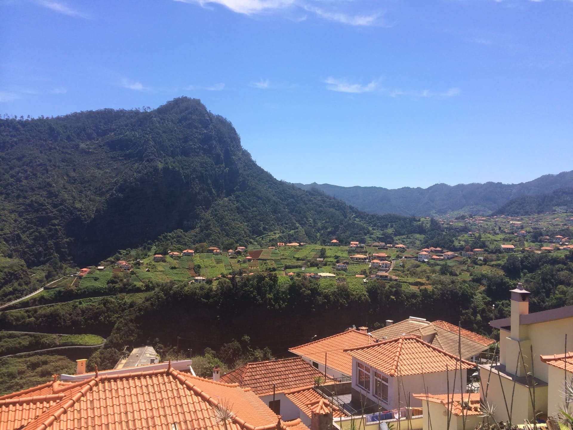 Os telhados de telha vermelha do Faial, com a falésia montanhosa coberta de floresta a erguer-se por trás