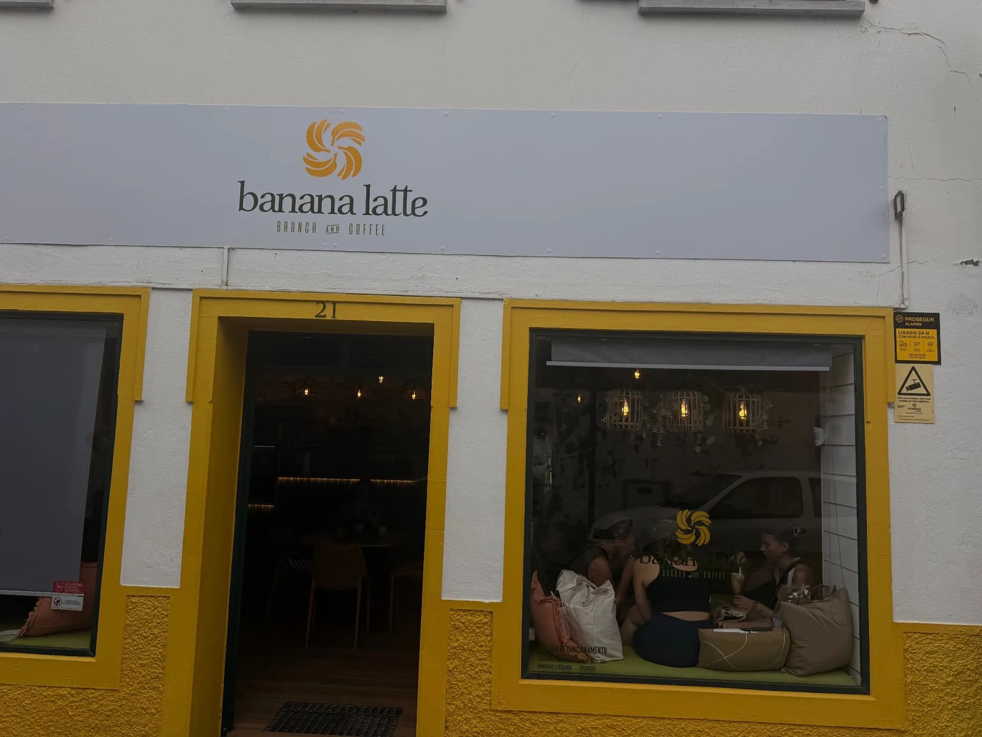 Fachada do «Banana Latte», um espaço de brunch e café em Machico, com caixilhos de janelas amarelos
