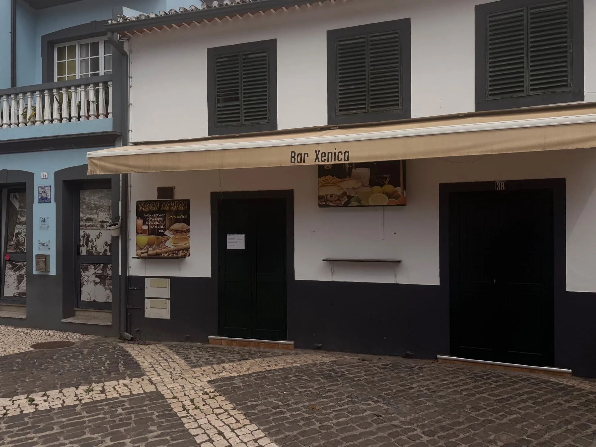 Fachada do Bar Xenica, com toldo, numa rua de calçada na cidade velha de Machico