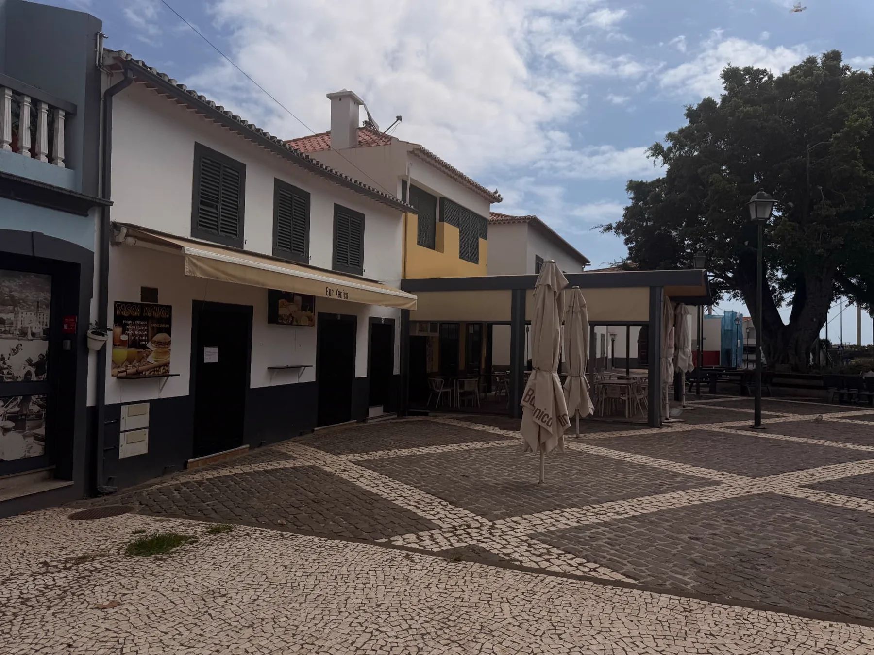 Bar Anico and outdoor terrace beside the patterned seafront promenade near Machico beach.