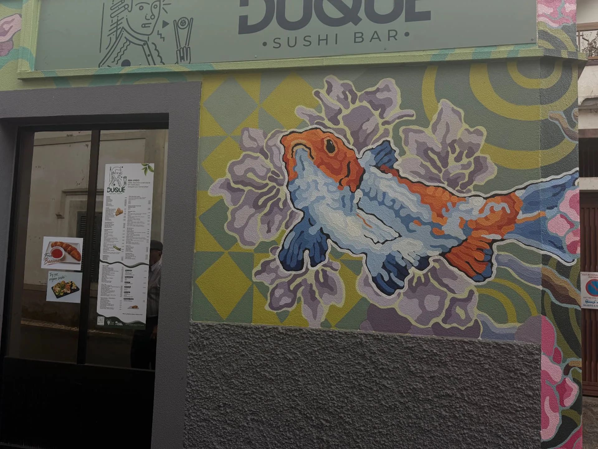 Grande plano do mural com carpas koi no Duque Sushi Bar, em Machico