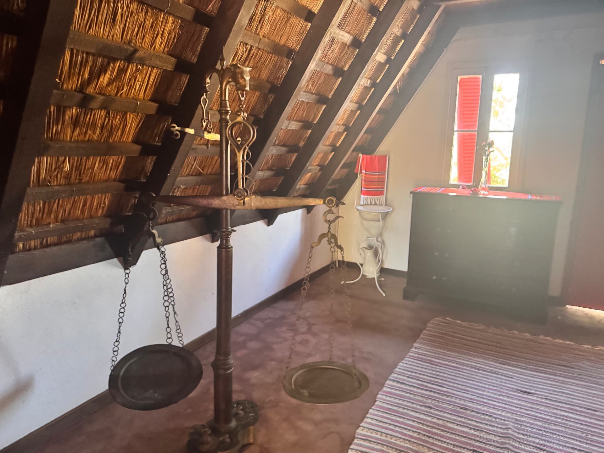 Balanças de latão antigas no interior de uma casa tradicional de Santana com telhado de colmo