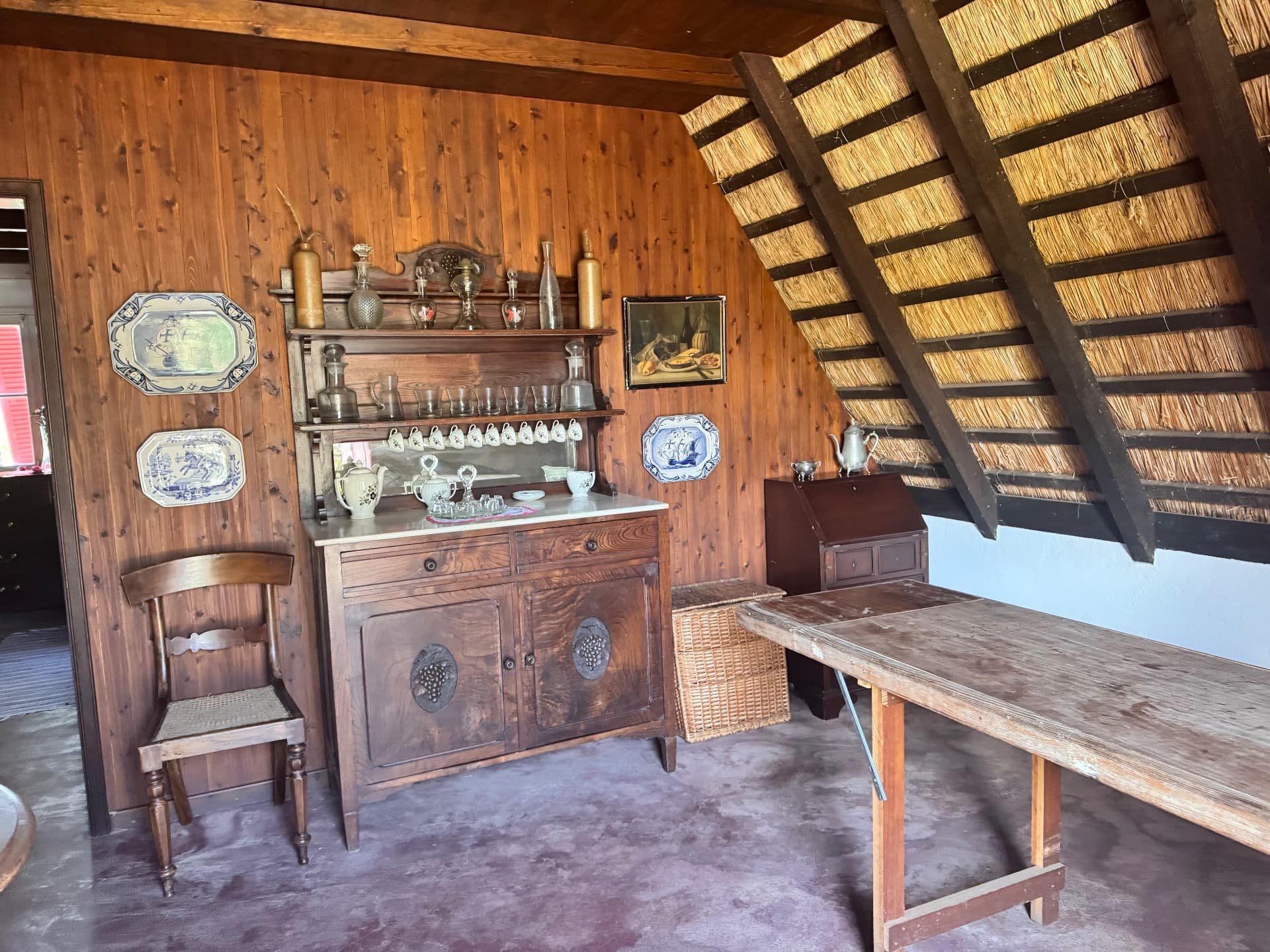 Cómoda antiga com pratos azuis e brancos e copos no interior de uma casa tradicional de Santana