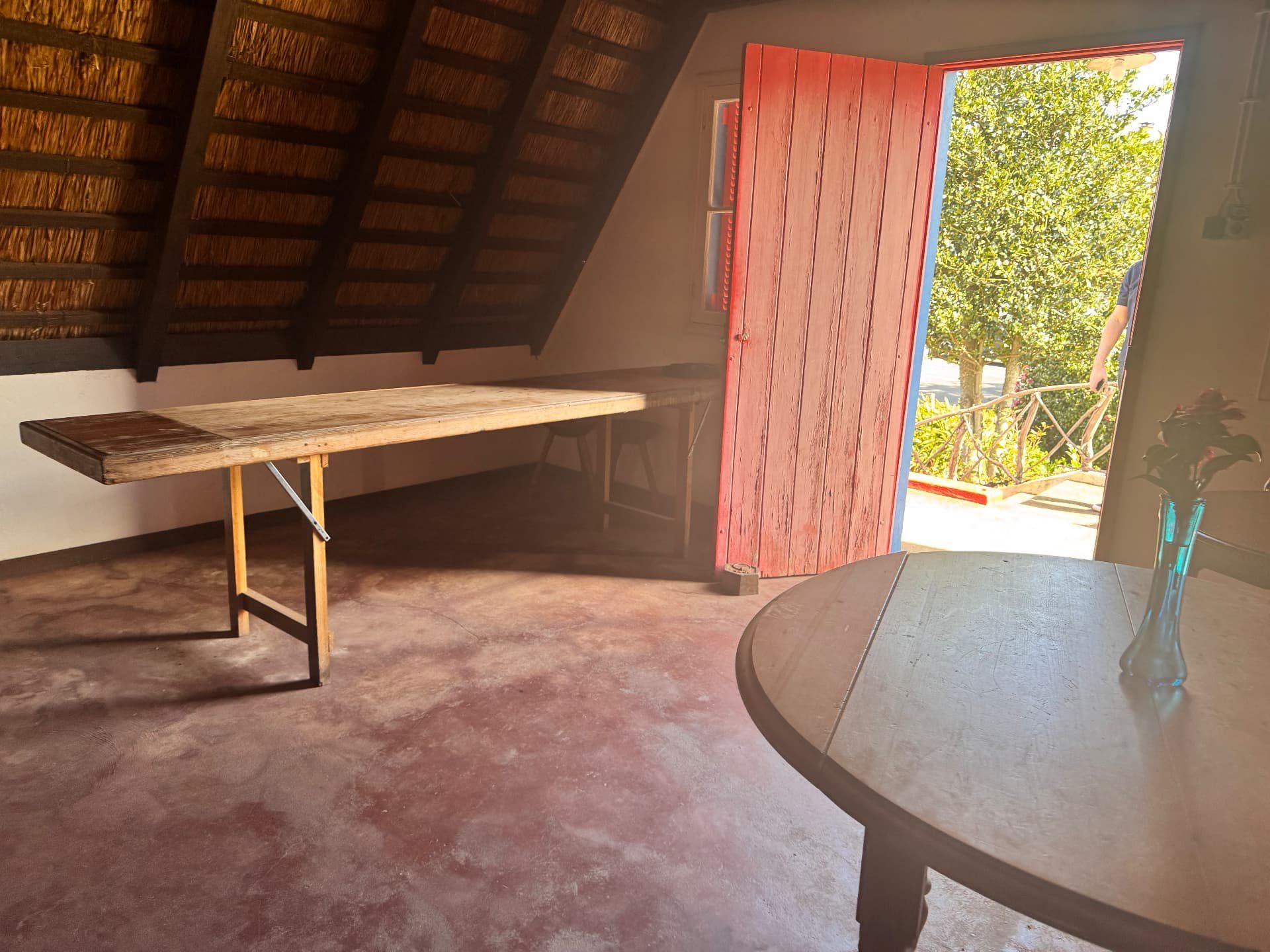 Porta de madeira vermelha aberta de uma casa tradicional de Santana, com vista para o jardim