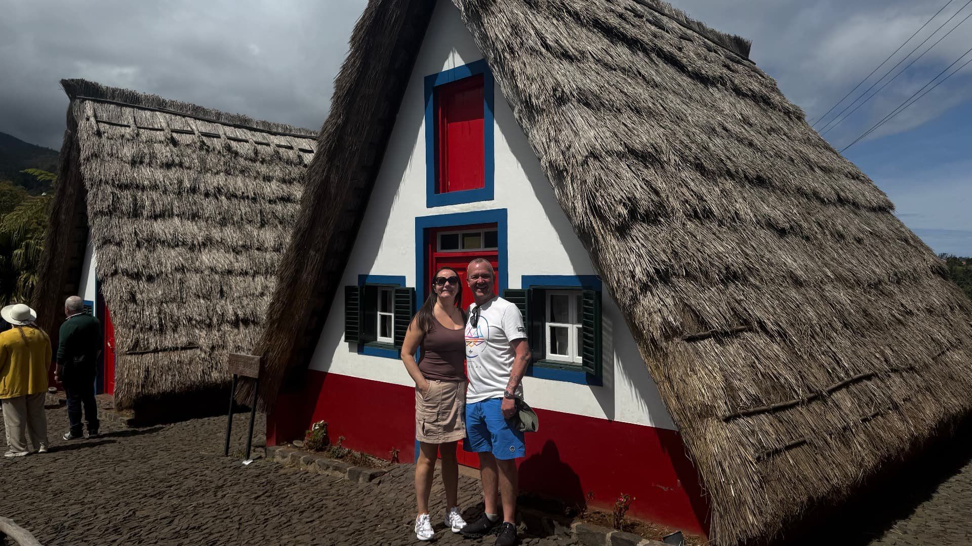 Traditional thatched palheiro houses in Santana, Madeira, with red doors and blue window trim