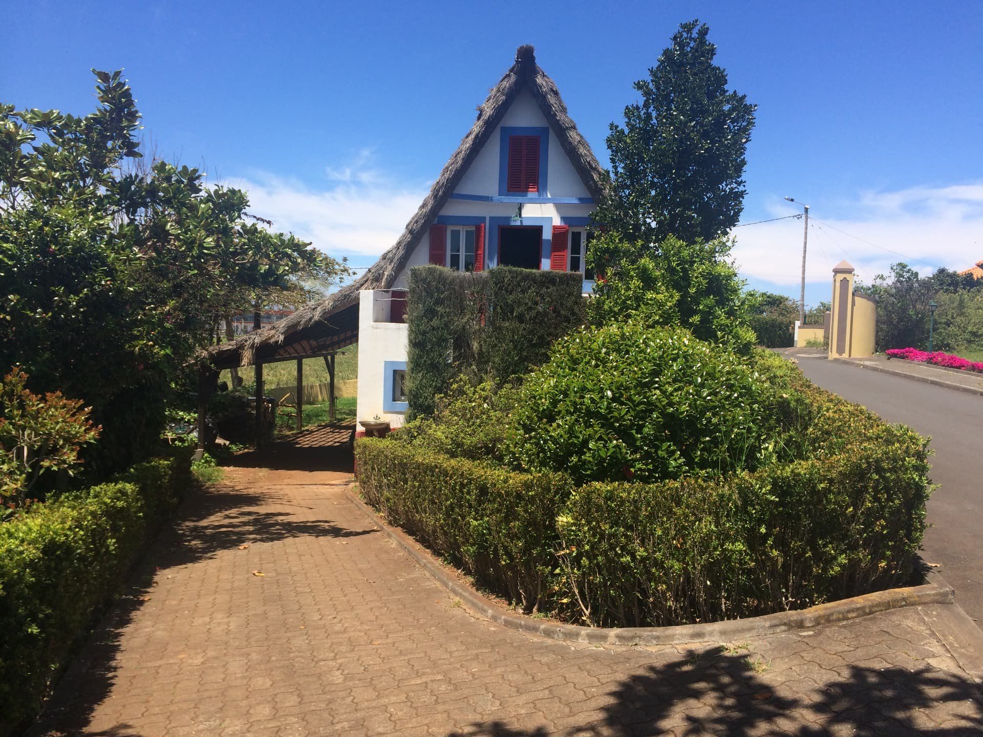 Caminho que conduz a uma casa de Santana triangular com telhado de colmo, com um abrigo com telhado de palha ao lado