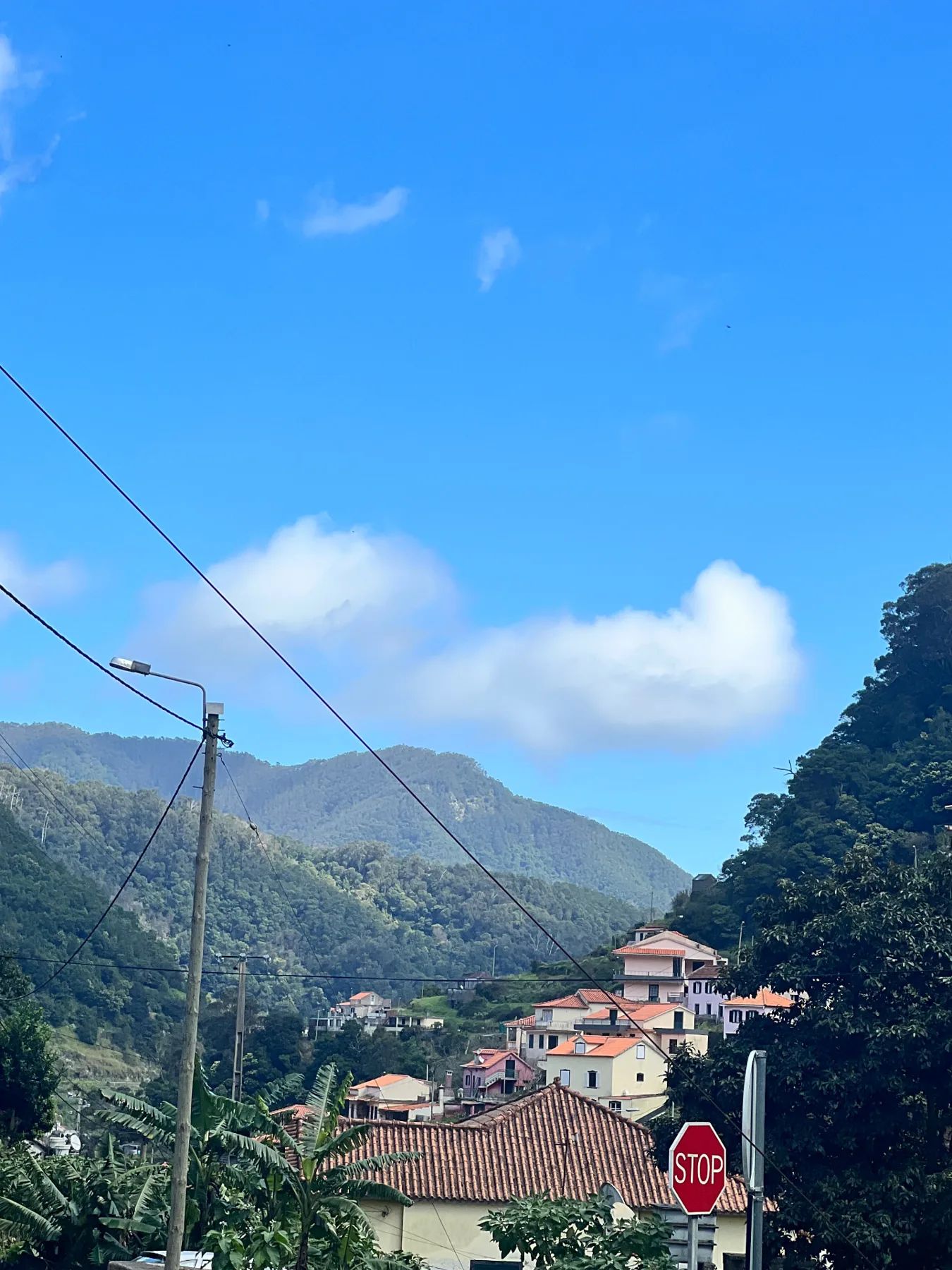Green mountains and clouds above village rooftops in Santo António da Serra