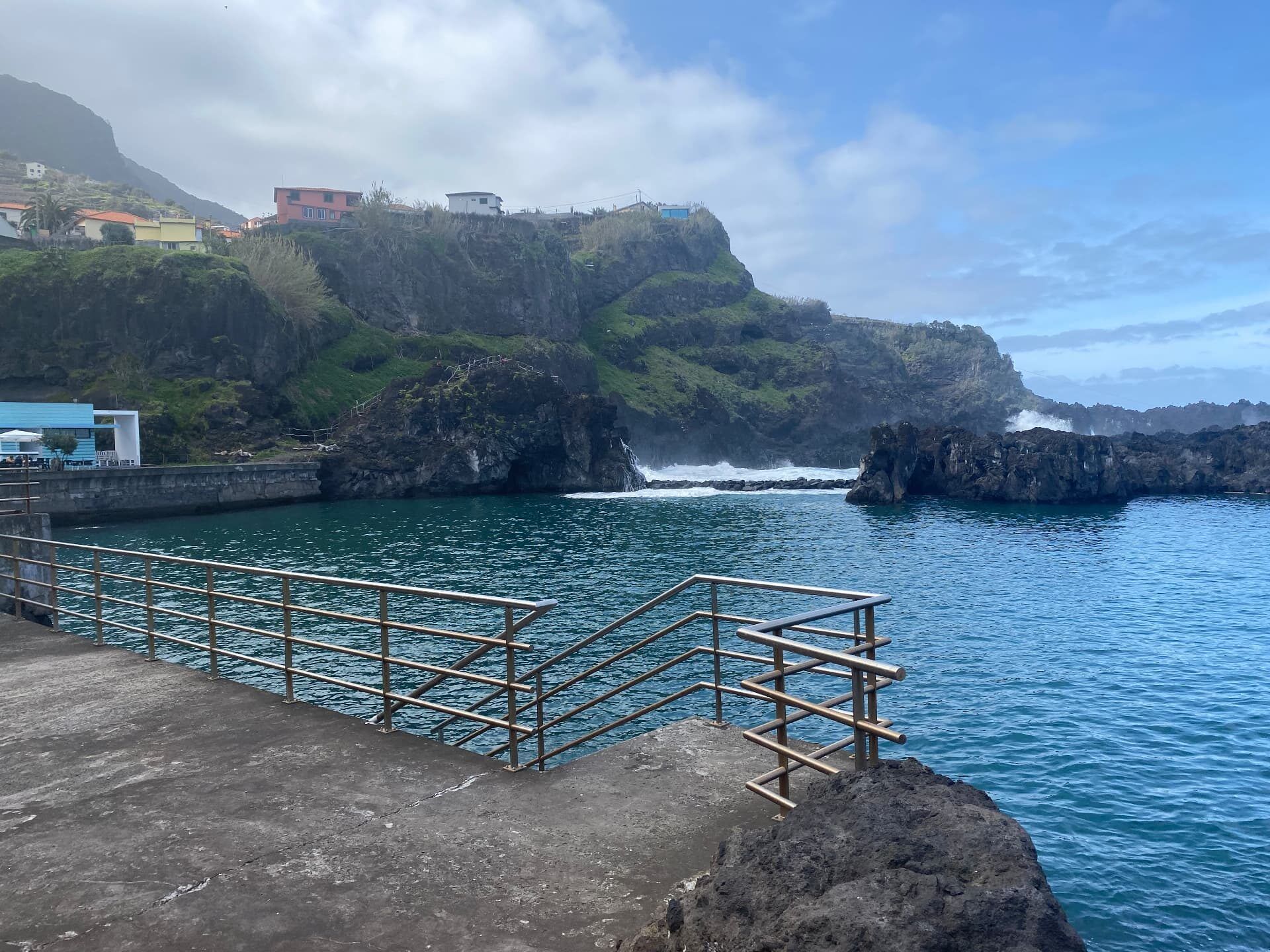 Natural sea pool and concrete bathing platform at Seixal on Madeira's north coast, with volcanic cliffs and village houses above