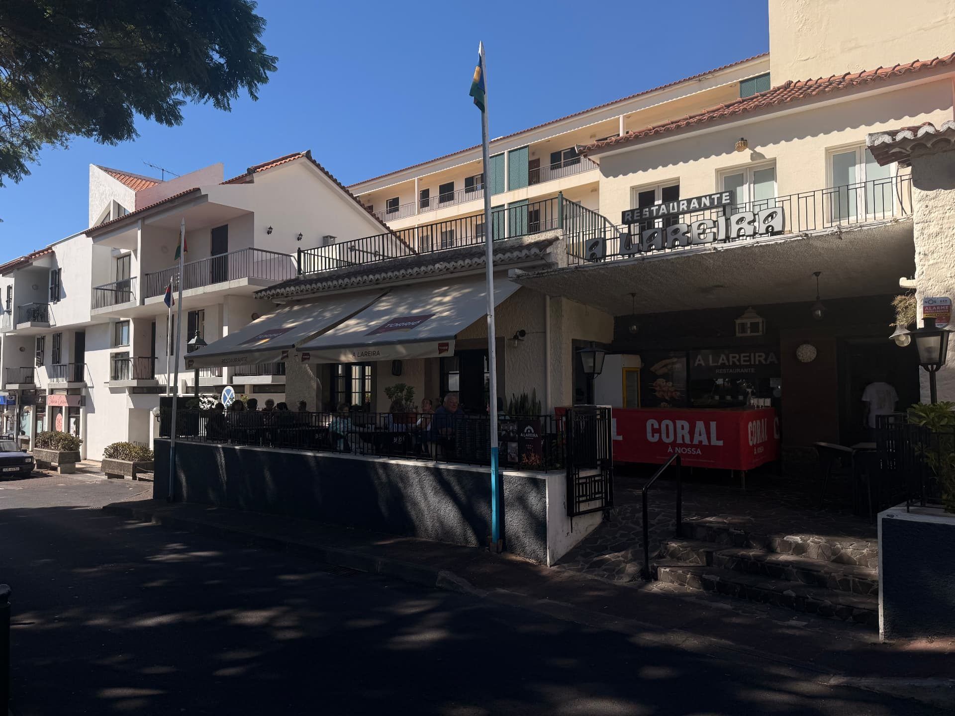 Street view of Caniço town centre with the A Lareira restaurant terrace and whitewashed buildings