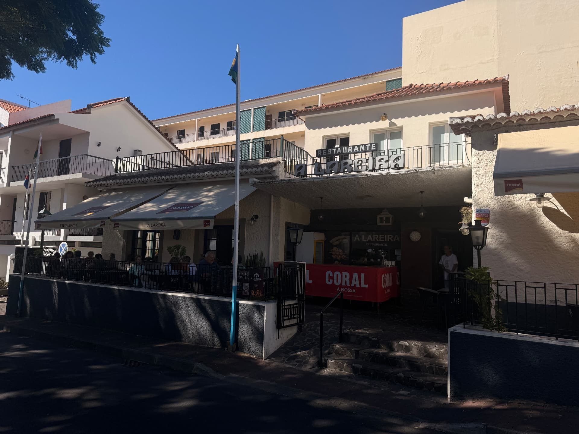 Restaurante A Lareira on Caniço town square, with diners on the shaded terrace