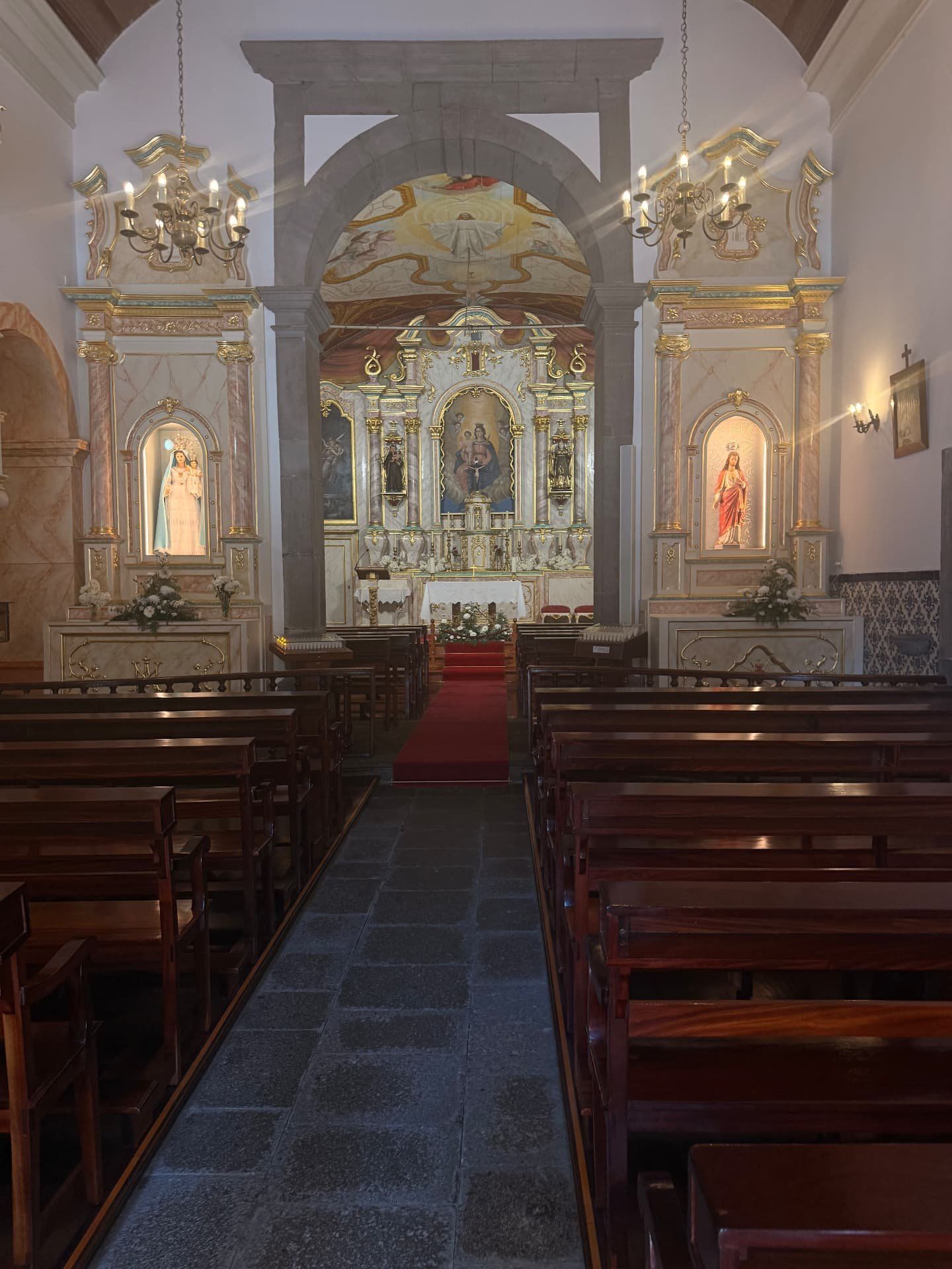 Nave da igreja paroquial do Curral das Freiras com bancos de madeira e altares laterais dourados
