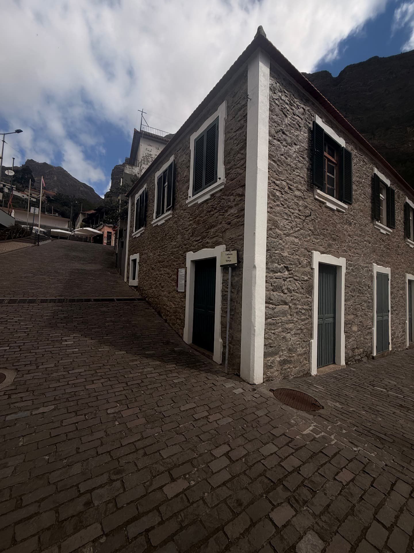 Casa da Família Rebolo, em pedra, no fundo da calçada da Ladeira da Igreja, com as falésias do vale atrás