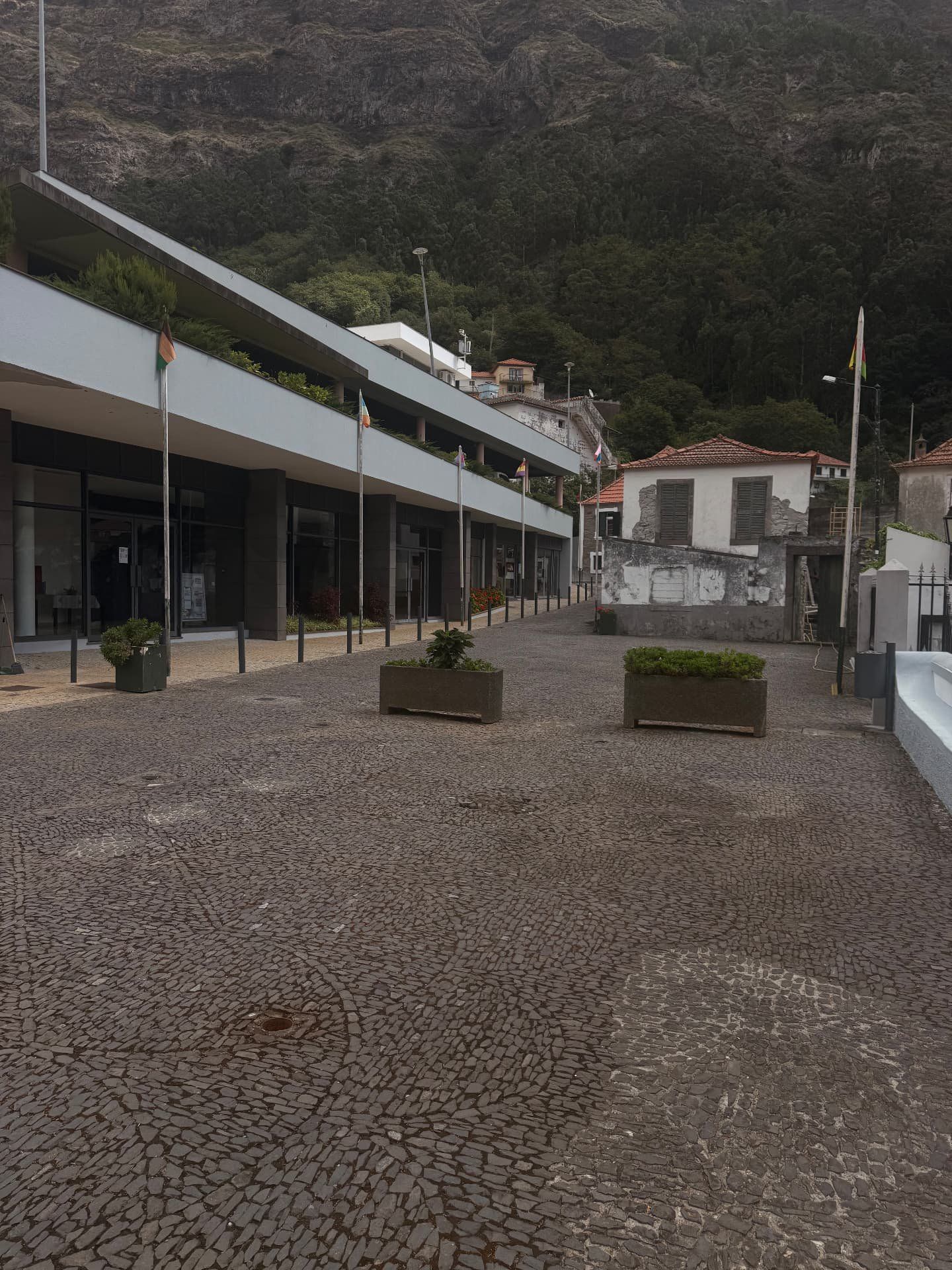 Praça calcetada no Curral das Freiras sob as encostas íngremes e arborizadas do vale