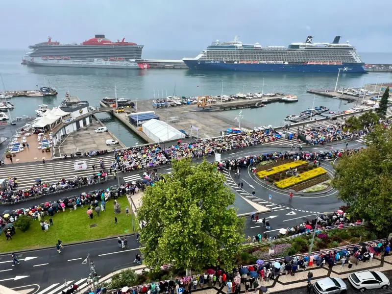 Two cruise ships, Virgin Voyages Resilient Lady and Celebrity Eclipse, docked at Funchal cruise port with crowds on the seafront promenade, Madeira