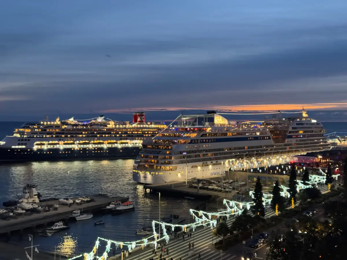 Cruise ships Queen Victoria and AIDAstella lit up at dusk in Funchal harbour with Christmas lights along the seafront, Madeira