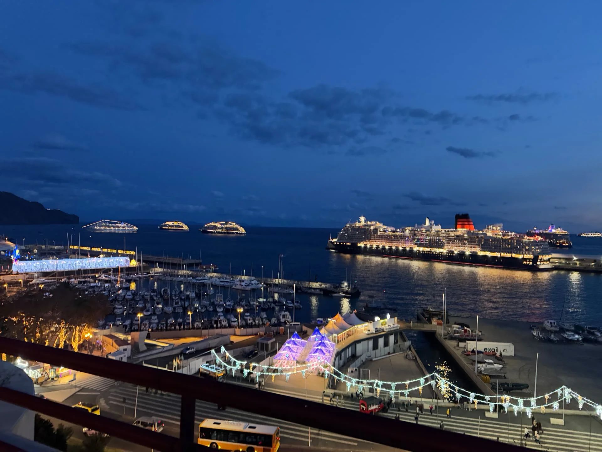 Queen Victoria cruise ship docked in Funchal harbour at twilight with other ships anchored offshore and festive lights on the quay, Madeira