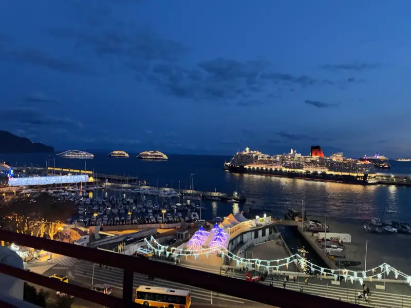 Queen Victoria cruise ship docked in Funchal harbour at twilight with other ships anchored offshore and festive lights on the quay, Madeira