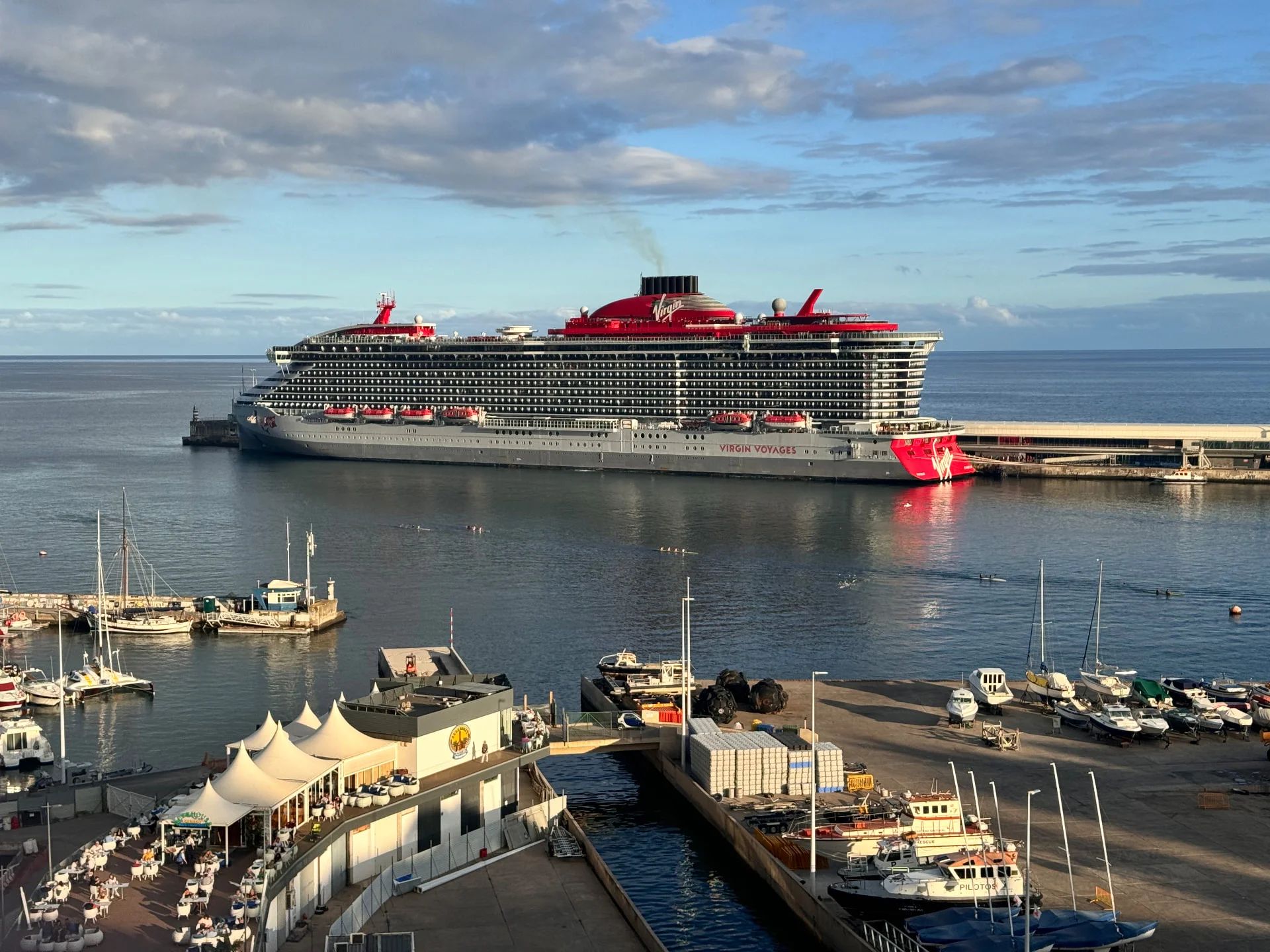 Virgin Voyages cruise ship Resilient Lady docked at Funchal cruise terminal with the marina and seafront restaurants in the foreground, Madeira