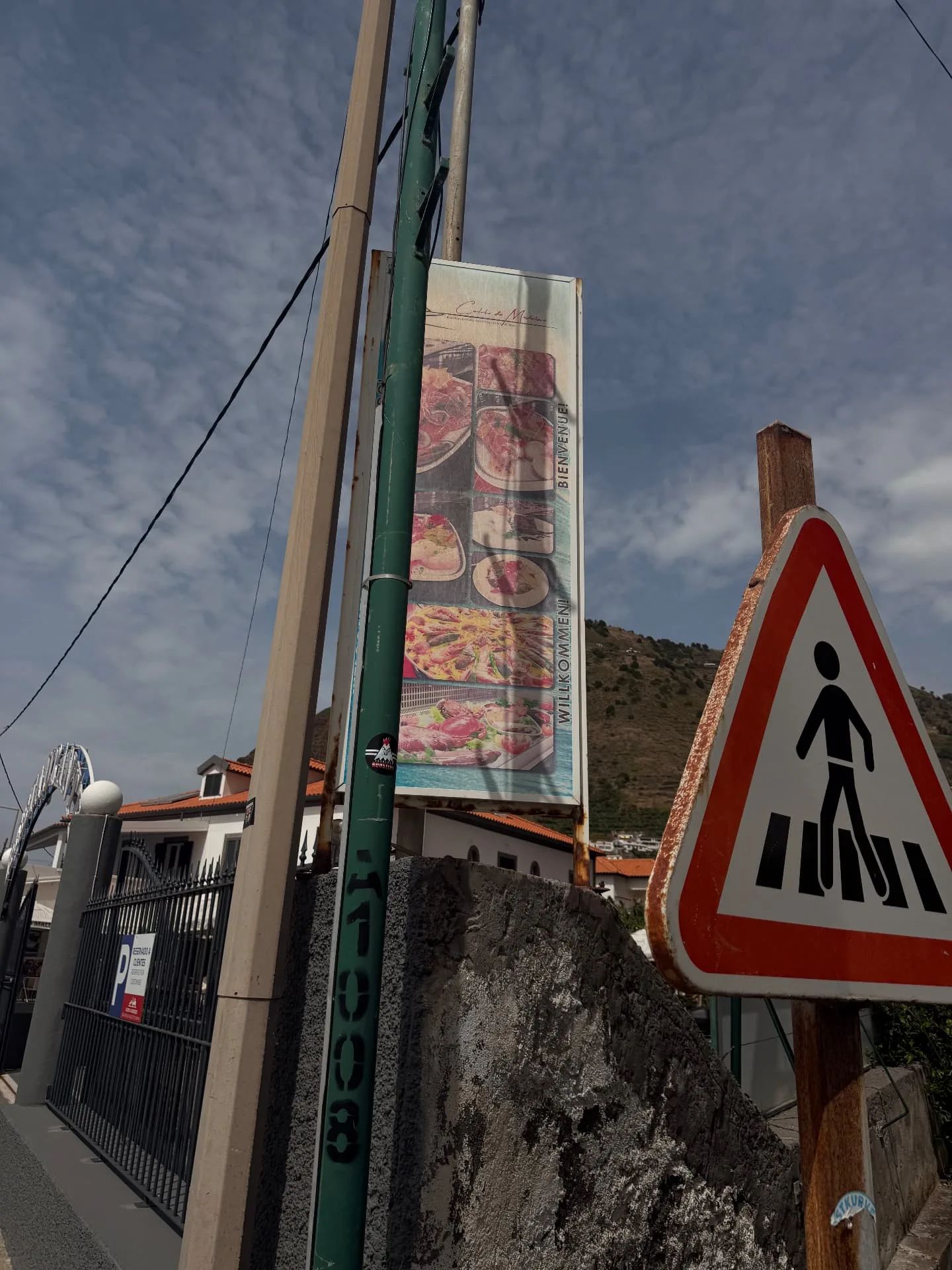 Placa de restaurante e sinal de passadeira na marginal da Madalena do Mar