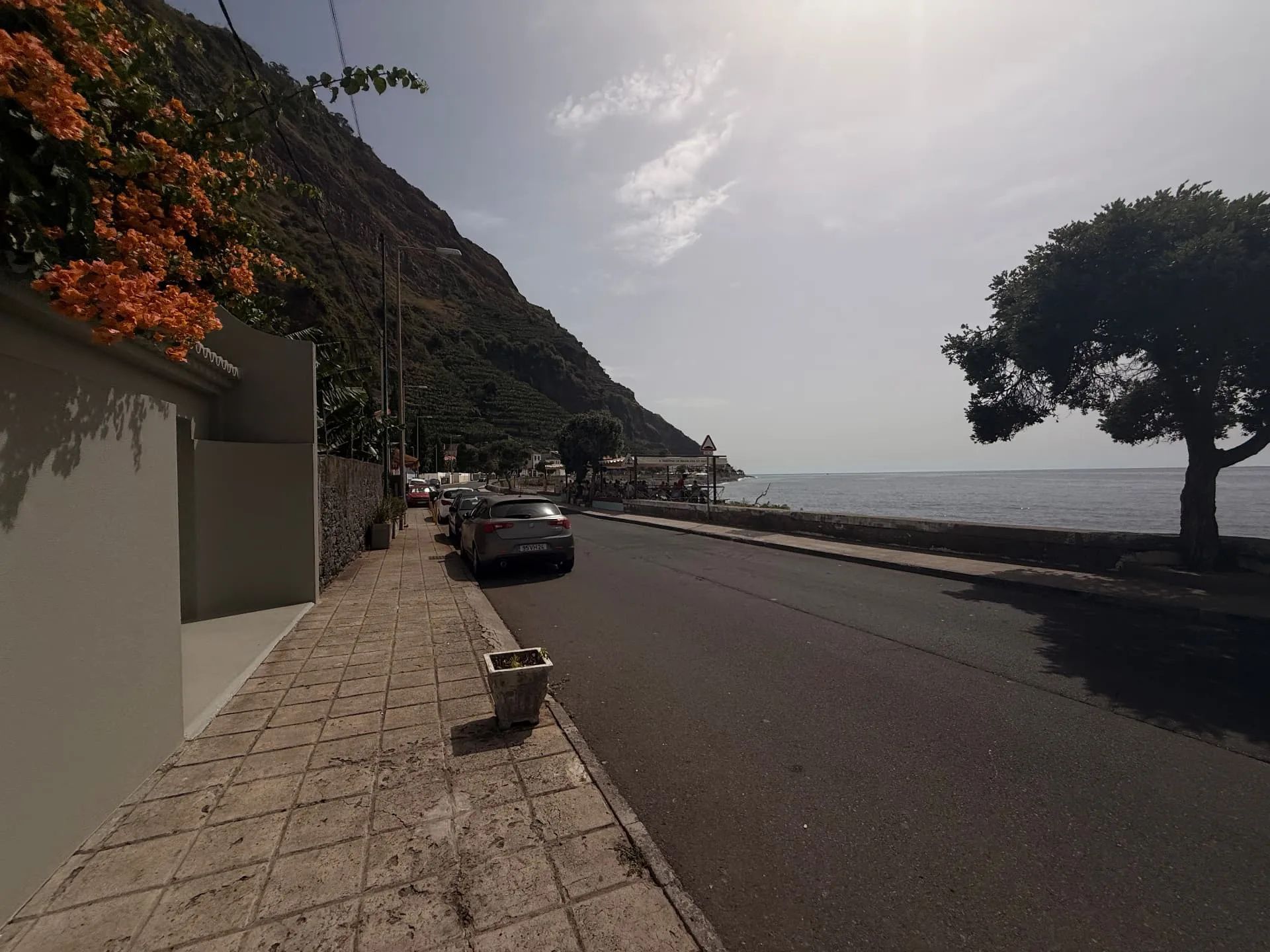 Marginal com buganvílias, carros estacionados e o Atlântico na Madalena do Mar